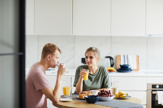 Junge Frau und ihr Mann trinken Orangensaft zum Frühstück