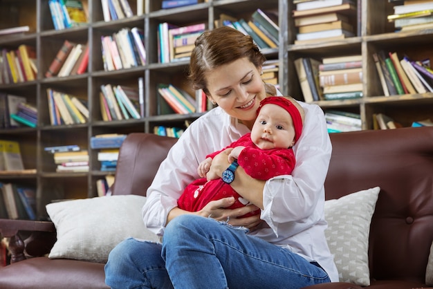 Junge Frau und ihre kleine Tochter auf der Couch in der Bibliothek zu Hause