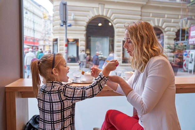 Junge Frau und kleines Mädchen essen Kuchen im Café