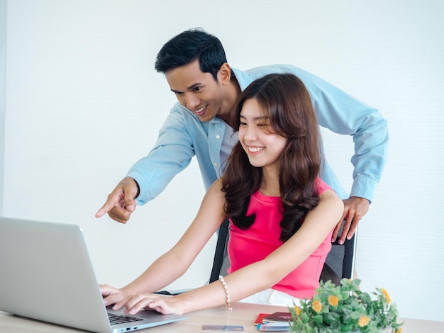 Junge Frau und Mann des glücklichen asiatischen Paares, die zusammen Tablet- und Laptop-Computer für Flugbuchungshotelzimmer und Reiseinformationen zu Hause verwenden, bereit, glückliches Feiertags-Sommerferienkonzept zu reisen