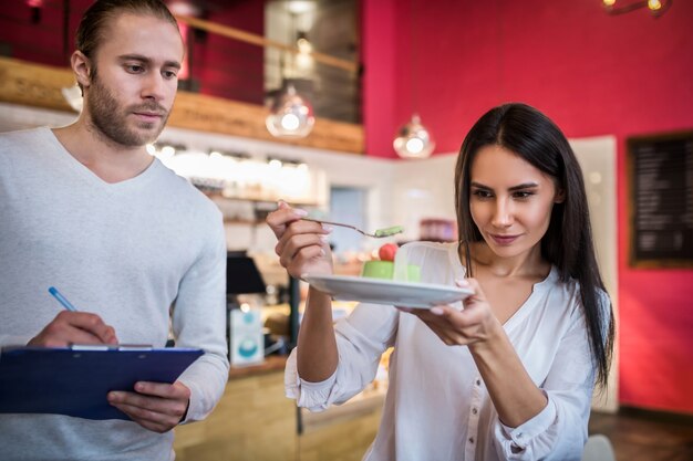 Junge Frau und Mann, die Nachtisch in einem Restaurant schmecken