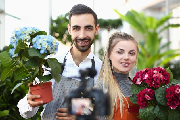 Junge Frau und Mann posieren für ein Foto mit luxuriösen Blumensträußen