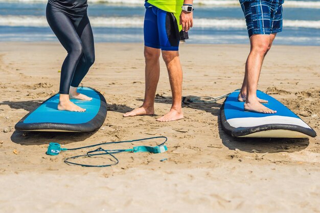 Junge Frau und Mann trainieren vor der ersten Surfstunde, um auf der Brandung zu stehen.