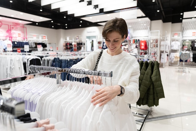 Junge Frau wählt Kleidung in einer Modeboutique