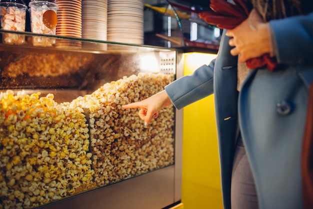 Foto junge frau wählt popcorn am kino aus