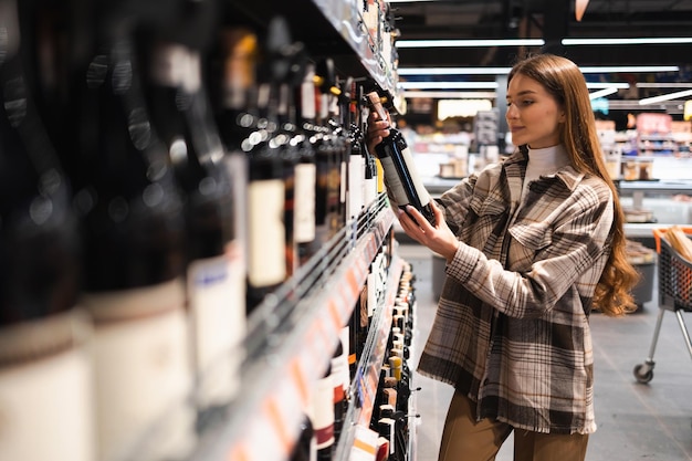 Junge Frau wählt Wein im Supermarkt aus