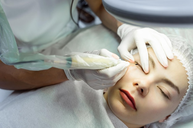 Junge Frau während der professionellen Permanent-Make-up-Behandlung zur Verbesserung der Wimpernlinie