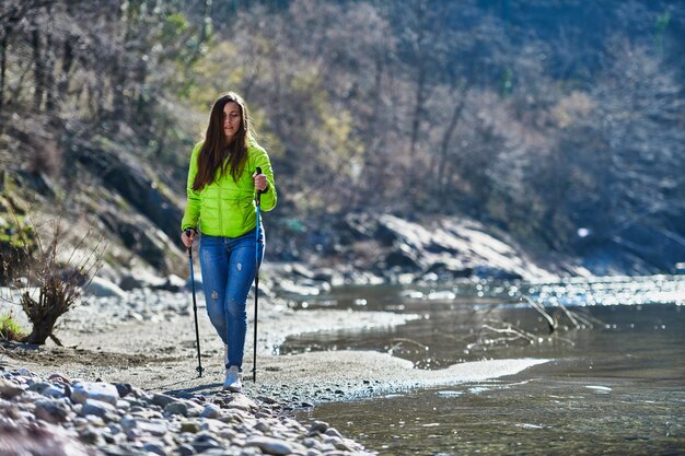 Junge Frau während einer Nordic Walking Wanderung an Bord eines Flusses