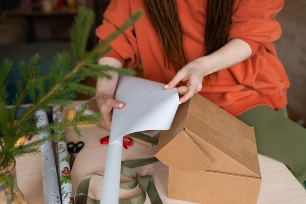 Junge Frau wickelt Weihnachtsgeschenke ein, zugeschnittenes gesichtsloses Foto