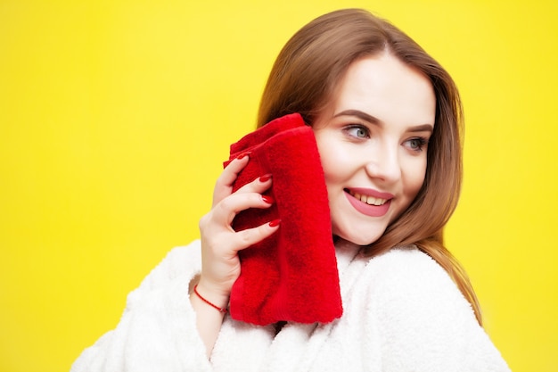 Junge Frau wischt Gesicht mit weichem Handtuch nach Spa-Behandlungen ab.