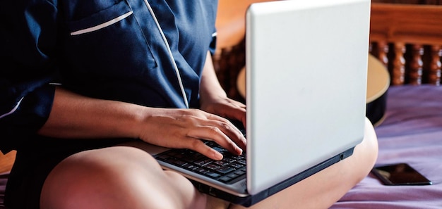 Junge Frau xAWorkingjunge Frau, die auf der Couch sitzt und einen Laptop zum Tippen verwendet