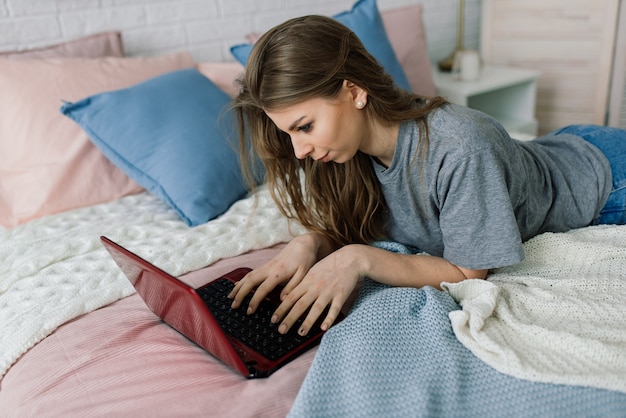 Junge Frau zu Hause, die mit einem Laptop arbeitet