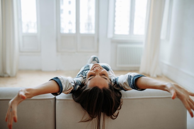 Junge Frau zu Hause im Wohnzimmer entspannt auf dem Sofa