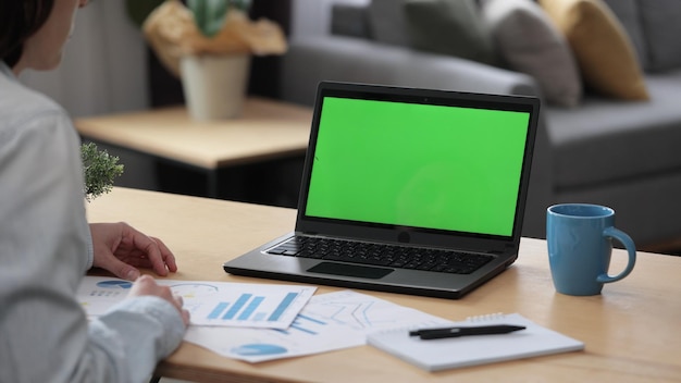 Foto junge frau zu hause. über die schulter laptop-greenscreen-ansicht.