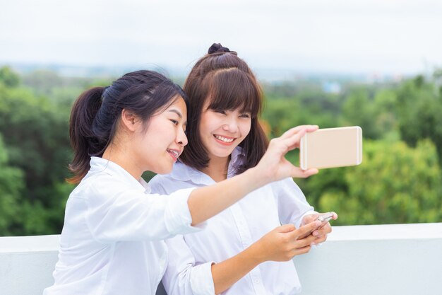 Junge Frau zwei genießen, ihr intelligentes Telefon zu benutzen, um selfies zu nehmen