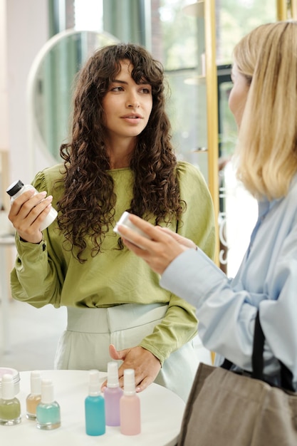 Foto junge frauen beraten sich beim durchsuchen des sortiments an beautycare-produkten