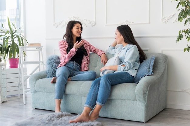 Junge Frauen, die auf Couch sitzen sprechen