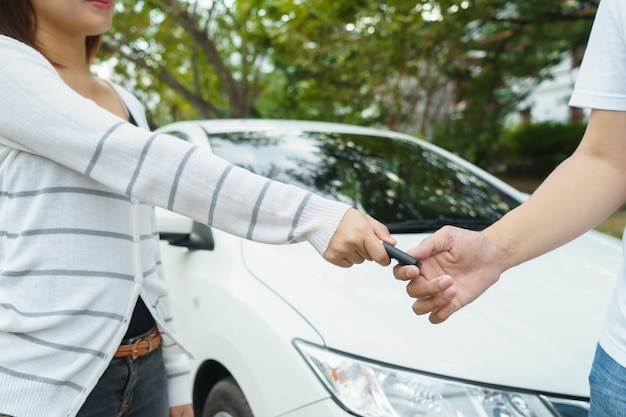 Junge Frauen, die dem jungen Mann im Zeichen des Autos ein Schlüsselauto geben.