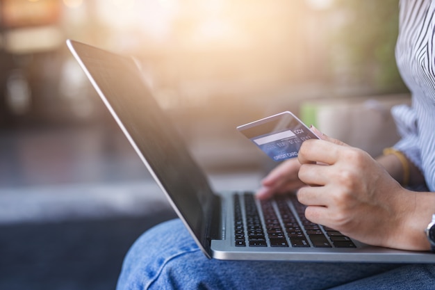 Junge frauen, die kreditkarte halten und laptop verwenden