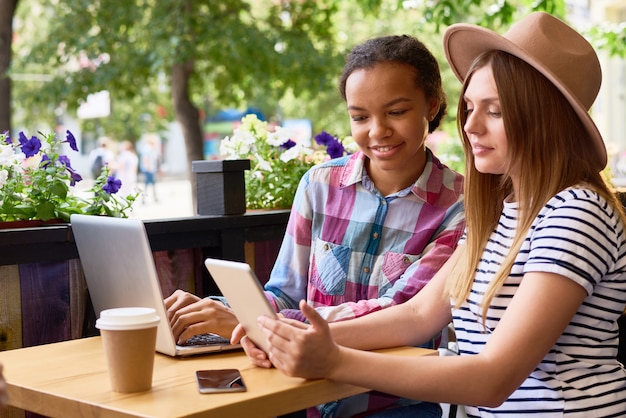 Junge Frauen, die moderne Geräte im Café verwenden