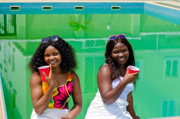 Junge Frauen, die sich am Sommertag am Pool amüsieren
