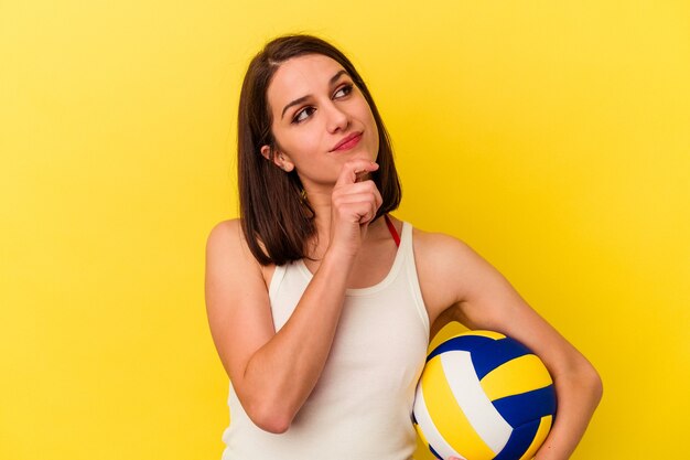 Junge Frauen, die Volleyball spielen und seitlich mit einem zweifelhaften und skeptischen Ausdruck schauen.