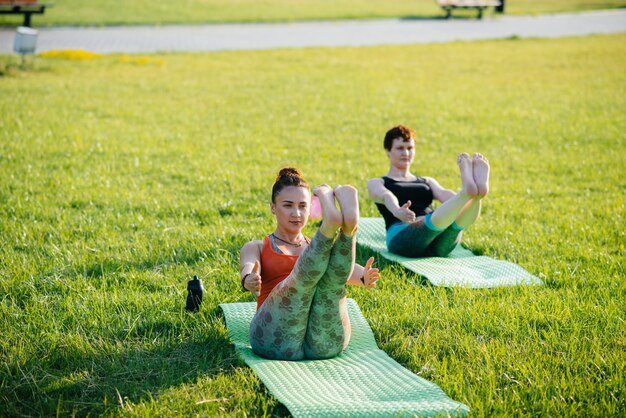 Junge Frauen, die Yoga draußen in einem Park tun