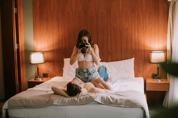 Junge Frauen fotografieren einen Mann im Bett