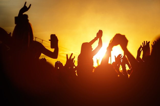 Junge Frauen genießen ein Rockkonzert Silhouette auf Sonnenuntergang Hände auf Openair
