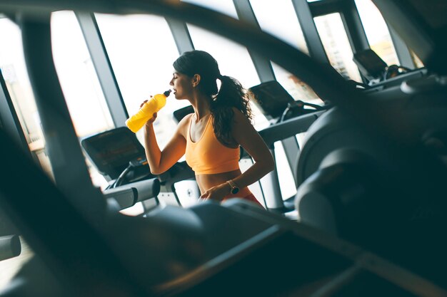 Junge Frauen im gelben Sporthemd trinken Wasser an der Turnhalle