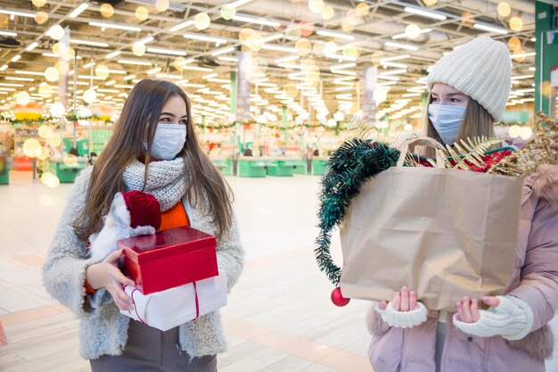 Foto junge frauen in medizinischen masken kaufen weihnachten im einkaufszentrum xmasferien in new