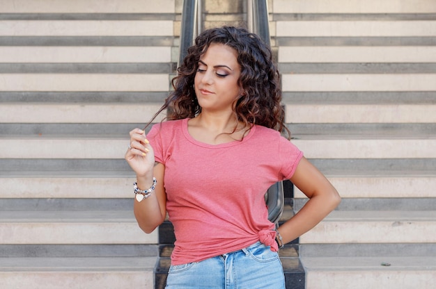 Foto junge frauen in t-shirt und jeans bleiben in der nähe der treppe und berühren haare