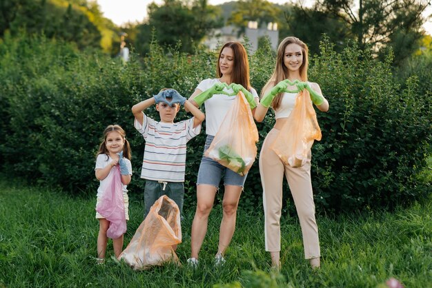 Junge Frauen mit Babys zeigen Herzen, nachdem sie bei Sonnenuntergang Müll im Park gereinigt haben Umweltschutz Abfallrecycling Sortierung von Müll