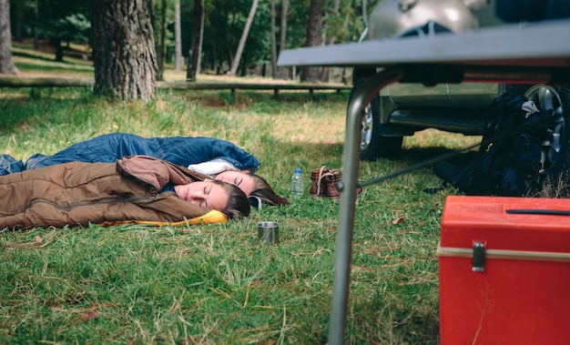 Junge frauen schlafen in der natur in schlafsäcken über dem gras auf dem campingplatz