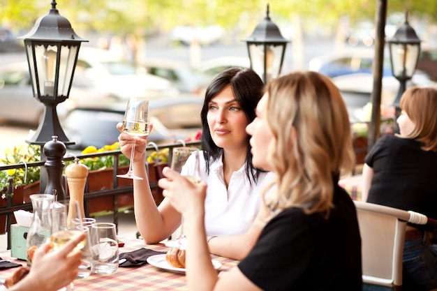 Foto junge frauen trinken einen weißwein in einer café-terrasse.