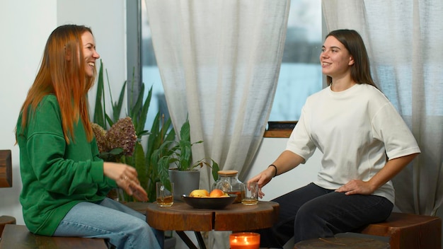 Junge Frauen trinken Tee und unterhalten sich im Café. Junge Studenten unterhalten sich in den Medien.