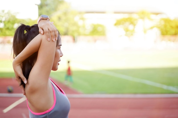 Junge Frauen wärmen sich morgens im Freien im Fußballstadion mit Sonneneruption und verschwommenem Hintergrund auf