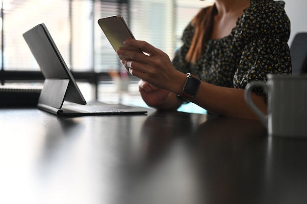 Junge Freiberuflerin mit Handy und Arbeit am Tablet