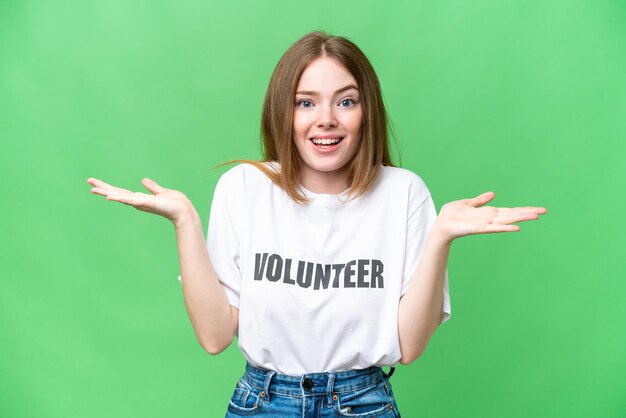 Foto junge freiwillige frau über isoliertem chroma-key-hintergrund mit schockiertem gesichtsausdruck