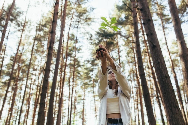 Foto junge freiwillige pflanzt einen wald und hält einen eichensämling in ihren händen