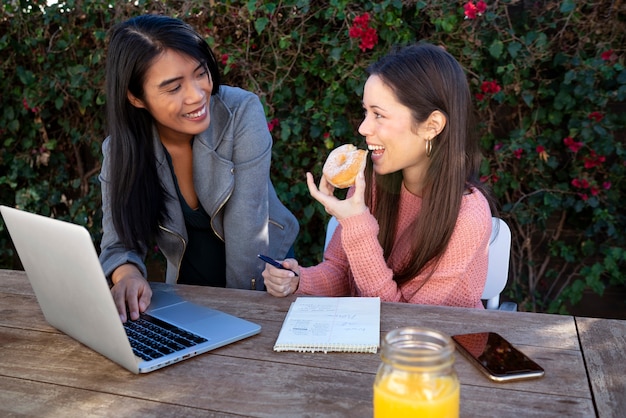 Foto junge freundinnen, die zusammen laptop im freien verwenden