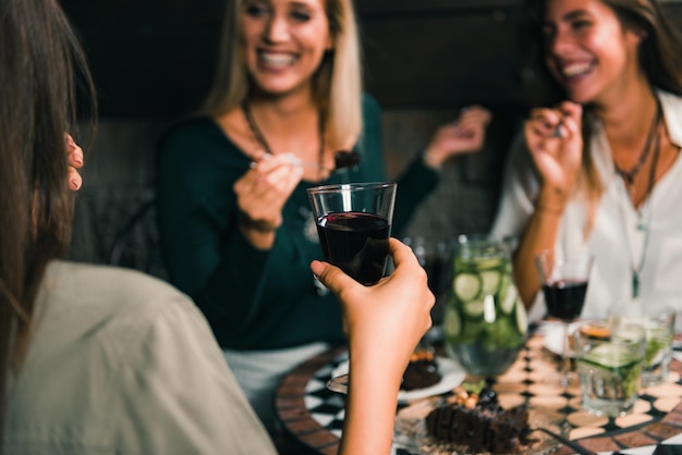 Junge Freundinnen essen Kuchen und trinken Wein