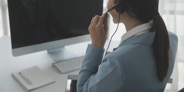 Junge freundliche Agentin mit Kopfhörern, die in einem Callcenter arbeitet