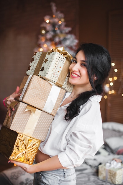 Junge fröhliche Frau, die Weihnachtsgeschenke hält