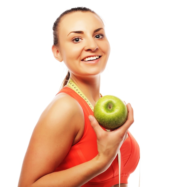 Junge fröhliche Frau in Sportkleidung mit Apfel, lokalisiert über weißem Hintergrund