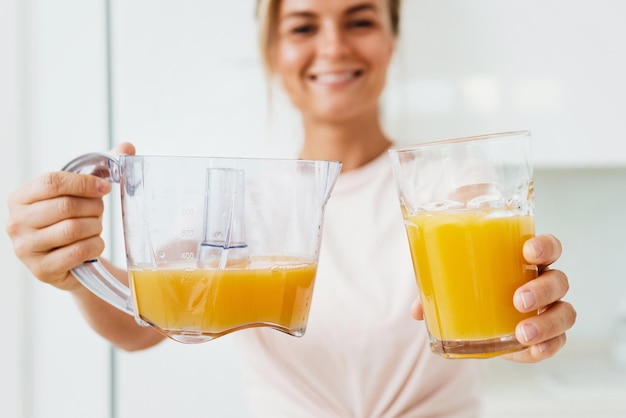 Junge fröhliche Frau mit großem Glas frischem Orangensaft