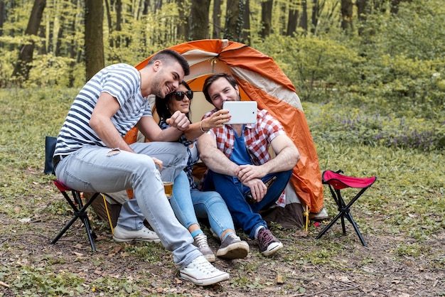 Junge fröhliche Freunde, die beim Picknicken ein Foto-Selfie machen