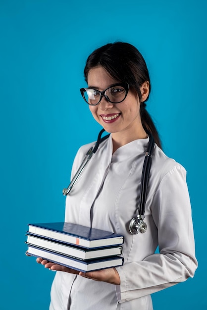 Junge fröhliche Ärztin mit Brille und Gesundheitsuniform mit Büchern