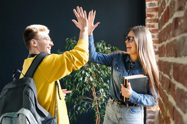 Junge, fröhliche Studenten, die sich fünf geben