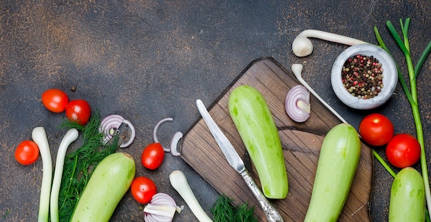 Junge Frühlings-Zucchini-Tomaten-Kräuter und Gewürze auf schwarzem Hintergrund